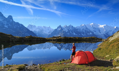 Hiker enjying the view at his red tent in the mountains near Chamonix, France.
