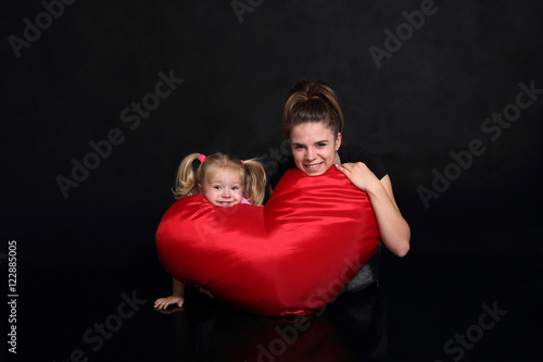 Uśmiechnięta matka z córką, poduszka czerwona, serce.