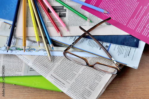 Glasses, color pencils and newspapers on the desktop. Очки, цветные карандаши и газеты на рабочем столе.