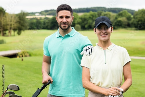 Couple standing with golf club and bag in golf 