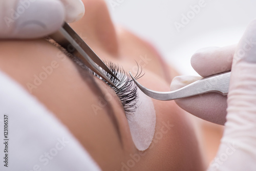 Skillful cosmetologist undergoing lash extension procedure