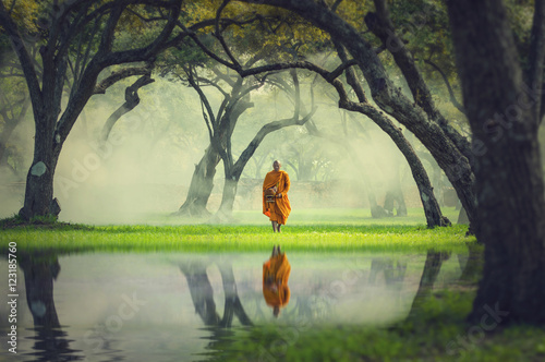 Monk hike in deep forest reflection with lake, Buddha Religion c