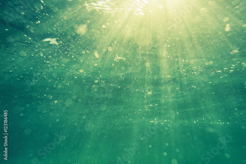Underwater shot with sunrays and bubbles in deep tropical sea