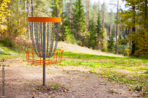 Disc golf (frolf) basket on a forest course in autumn with a shallow depth of field