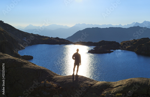 Man looking over a lake, Lac Cornu, toward the sun.