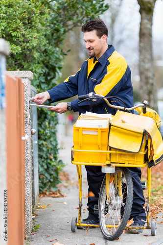 Postbote bei Zustellung von Briefen an Briefkasten von Empfänger