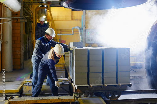 Factory workers push a cart with bricks in kiln