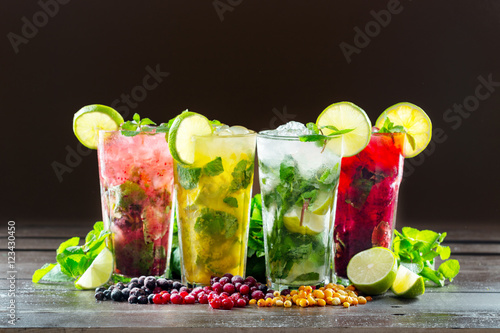 Different types of mojito cocktail on dark brown background