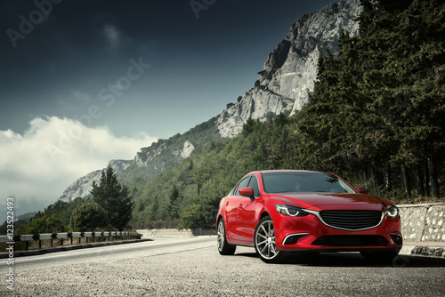 Red car standing on the road near mountains at daytime