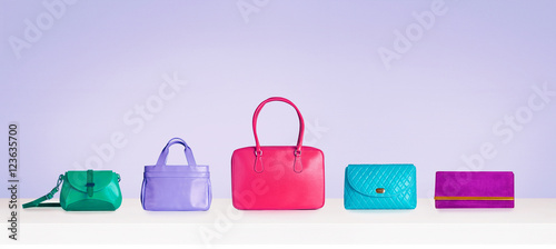 Colorful bag purse collection isolated on bright purple background. 