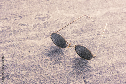 Round sunglasses on stone table, Retro eyewear. Still life of cool design accessory.