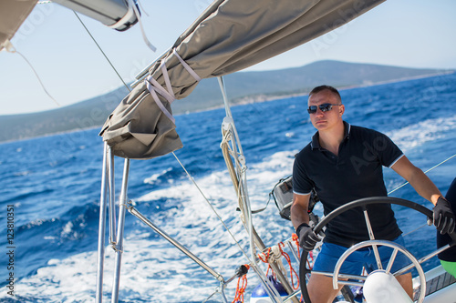 Young sailor skipper manages sailing vessel during regatta race in the open sea.