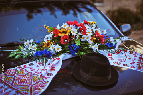 Black hat, wedding towel and flowers lie on the black hood