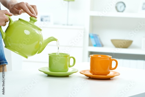 Pouring water from tea kettle to mug high key
