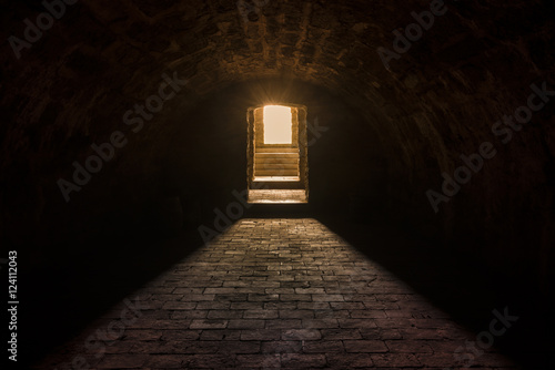 Basement interior with stone floor - Medieval European basement interior, with round ceiling and stone floor, with strong sun lights at the entrance