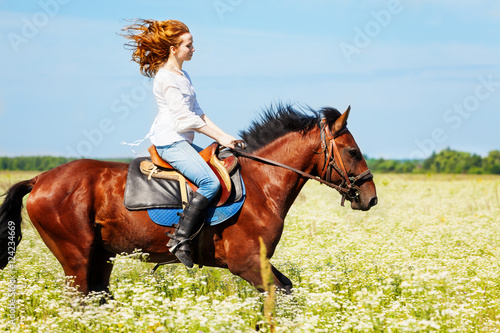 Young woman galloping horseback in flowery meadow