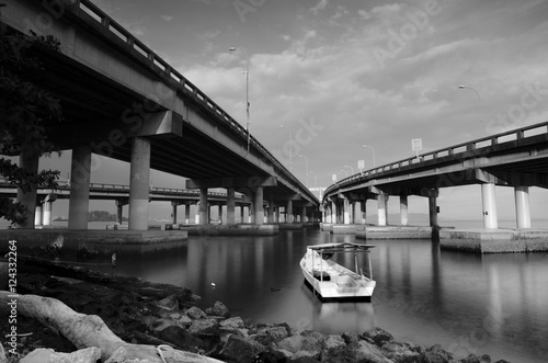 black and white image a boat anchored between two bridge.blurred
