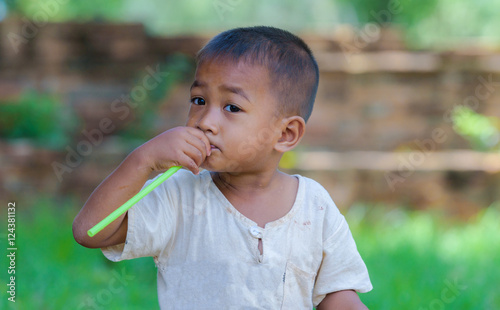 Asian boy with straw in mouth,dirty with innocent play.