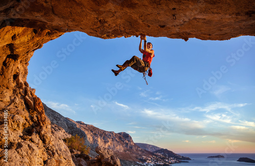 Male climber gripping on handhold while climbing in cave. Rock climbing without rope.