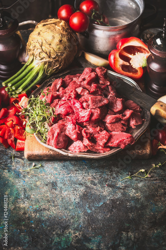 Raw Beef goulash of young bulls with vegetables and cooking ingredients on dark rustic background , preparation, border