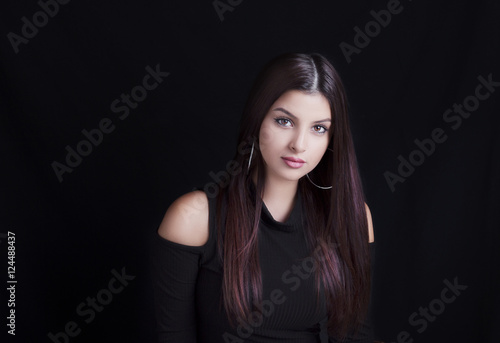 Young attractive woman with long black hair on black background.