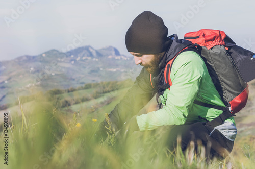 Hiker is looking at flowers on the ground