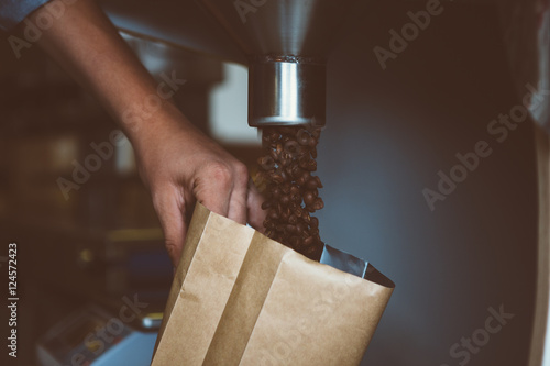 close-up of man filling package with coffee beans