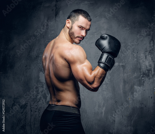 Aggressive shirtless boxer on grey background.