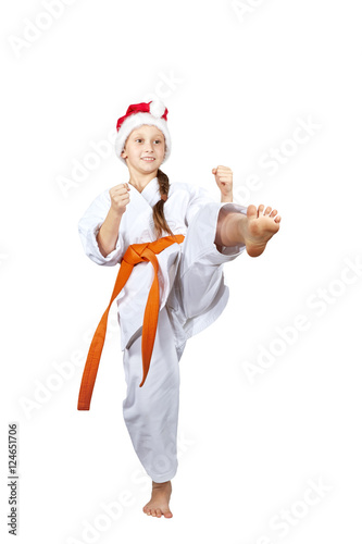 Sportswoman in a cap of Santa Claus hits a kick leg