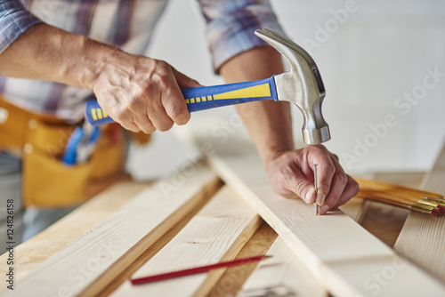 Carpenter with hammer hitting nails.