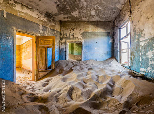 Room full of sand with colored door in the ghost town of Kolmanskop, Namibia