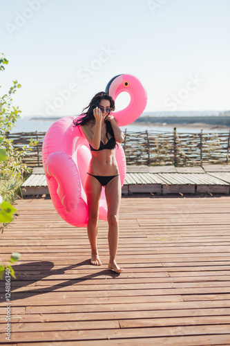 beautiful woman holding sprinkled pink inflatable flamingo float 20s