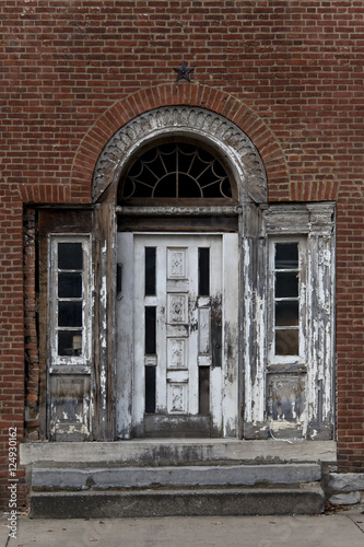 Elegant, weathered white door with aging, ornate details on vintage brick wall