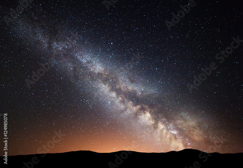 Night landscape with amazing Milky Way and yellow light at mountains. Starry sky with hills at summer. Beautiful Galaxy.l Universe. Space background
