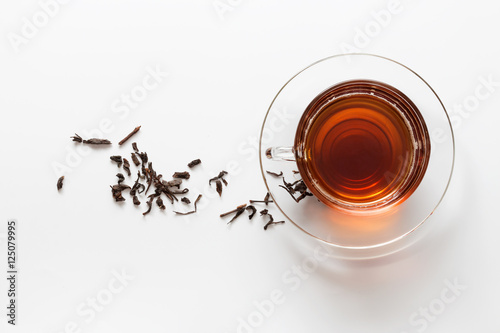 transparent glass cup with tea on the saucer with dry tea leaves