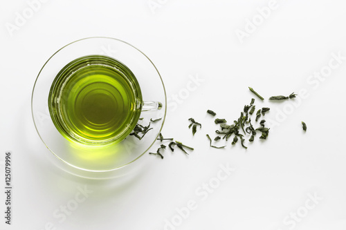 transparent glass cup with green tea on the saucer with dry tea