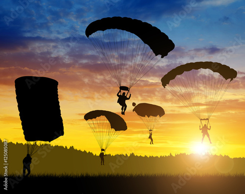 Silhouette skydiver parachutist landing at sunset