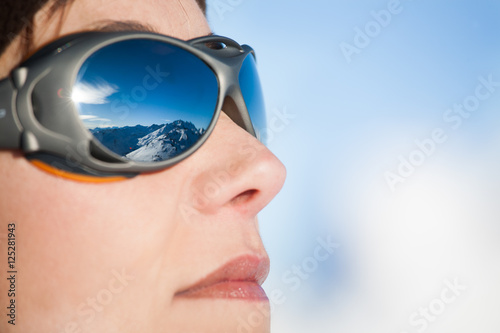 visage de femme avec des lunettes de soleil et les montagnes qui se reflètent dedans