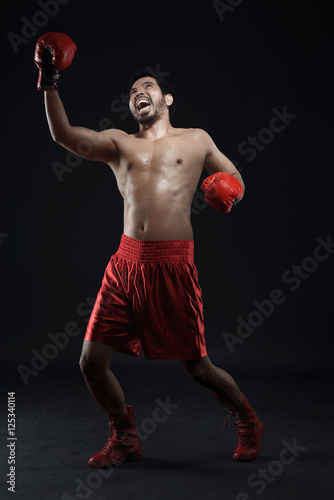 Asian boxer celebrating a win with boxing gloves