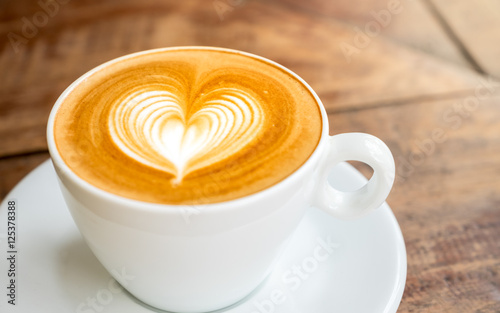 Zamknij się biały kubek kawy z latte art kształcie serca na zakładce drewna
