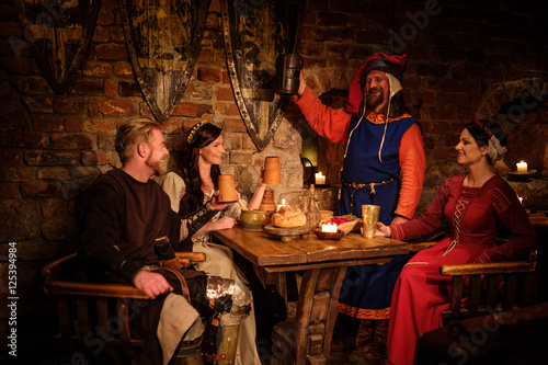 Medieval people eat and drink in ancient castle tavern