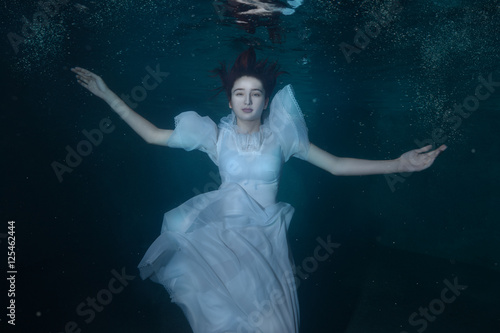 Woman in a white dress under water.