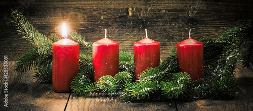 Ersterer Advent: eine leuchtende Kerze vor einem Holzhintergund