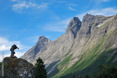 Wooden troll and mountain crest against the blue sky. Trollstigen.