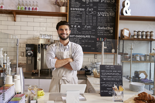 Business owner at the counter of coffee shop, arms crossed