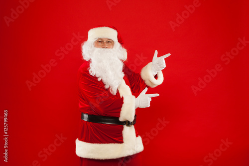 Santa Claus pointing in blank a place, red background