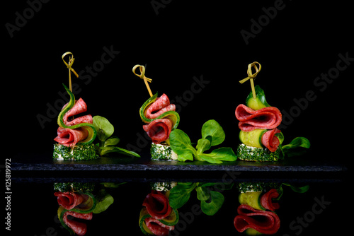 canape salami cucumber on black background with reflection