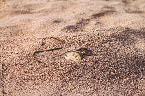 Still life - Antique rotten pocket watch buried partial in the sand