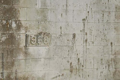 Building's birthdate (1968) on dirty cinderblock wall