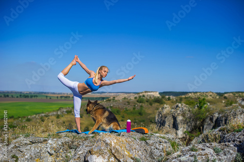 beautiful blonde girl practices yoga with dogs, german shepherd